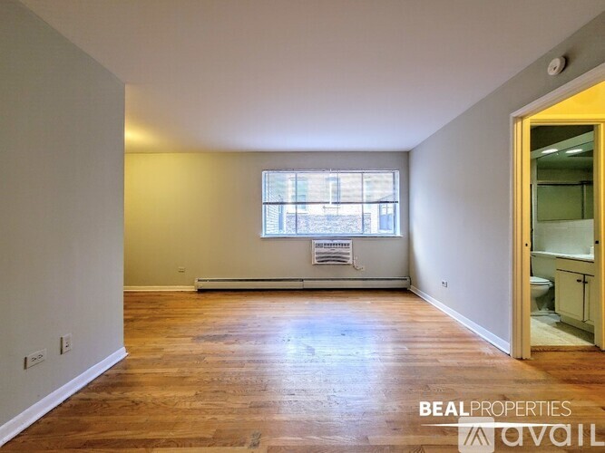 A room with wooden floors and a window with blinds.