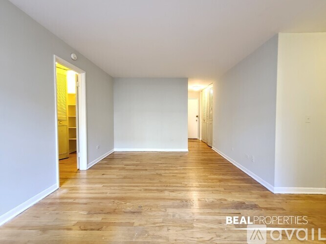 A spacious room with wooden flooring and white walls, with a doorway leading to another room.