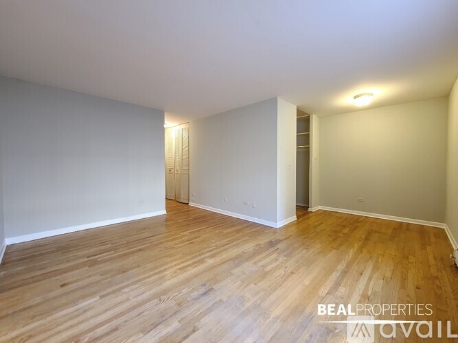 A room with wooden flooring and white walls, with a door on the right side.