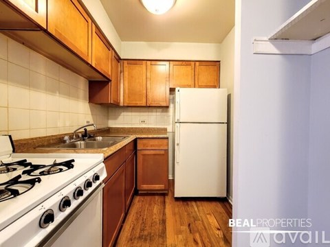 A kitchen with a white stove top oven, white refrigerator, and wooden cabinets.