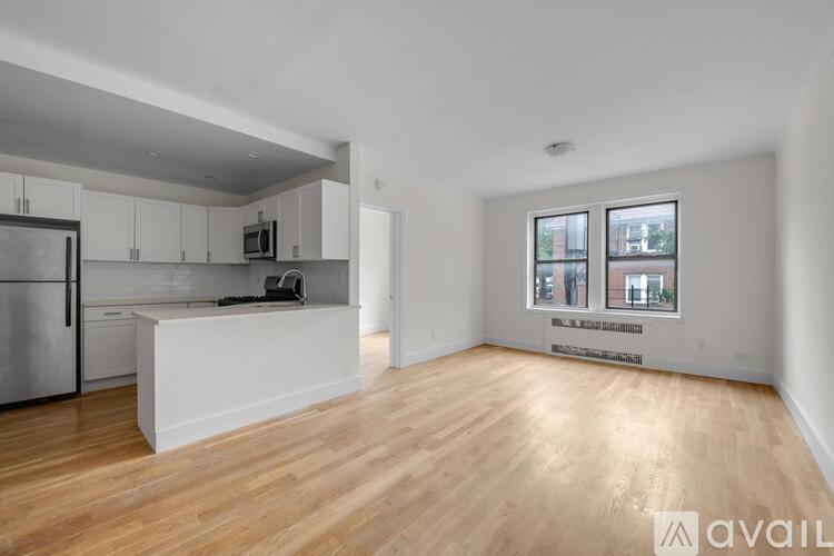 A spacious kitchen with wooden floors and white cabinetry.