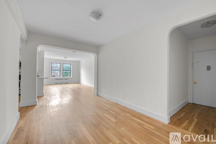 A spacious room with wooden flooring and white walls.