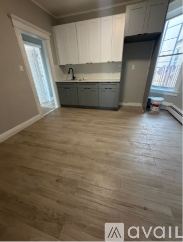 A kitchen with wooden floors and white cabinets.