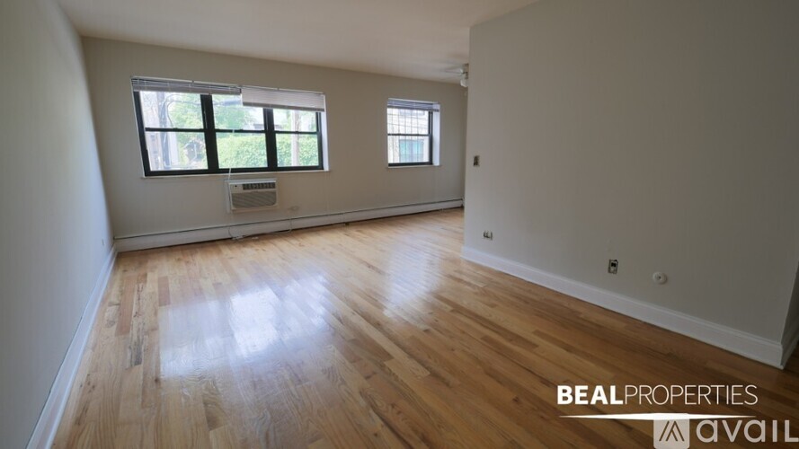 A room with wooden flooring and two windows is available for rent.
