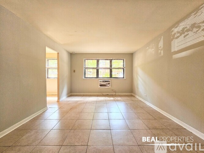 A spacious room with tiled flooring and a window with blinds.