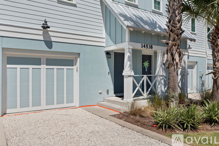 A house with a blue and white exterior and a palm tree in front.