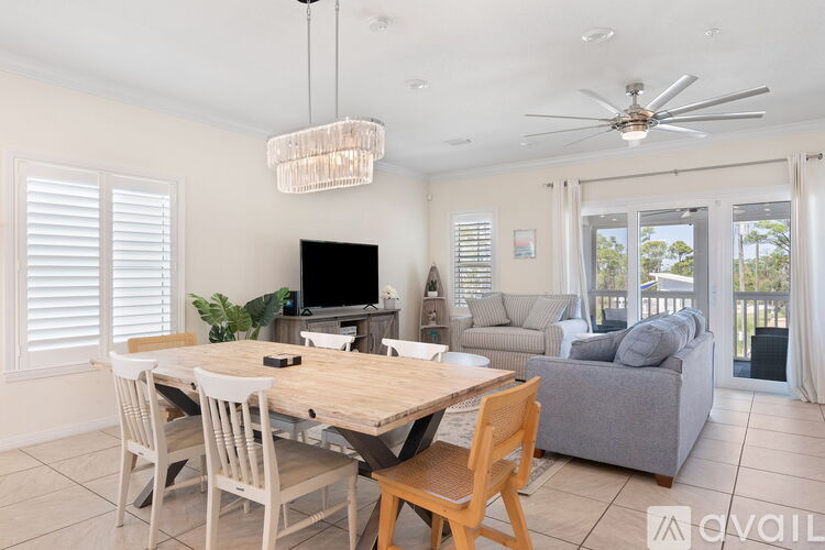 A dining room with a wooden table and chairs, a television, and a ceiling fan.