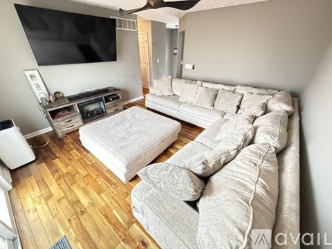 A living room with a grey couch and a television on the wall.