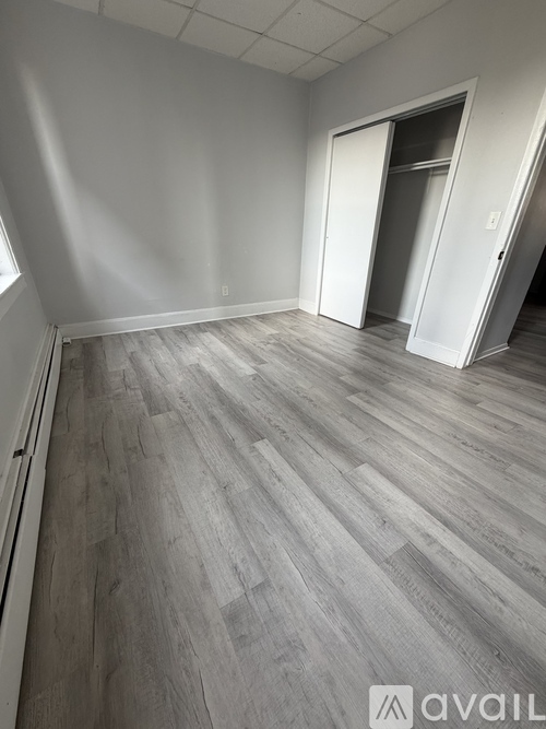 A room with wooden flooring and two open doors.