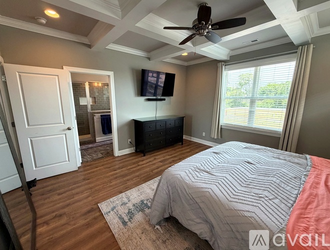 A bedroom with a ceiling fan and a bed with a striped comforter.