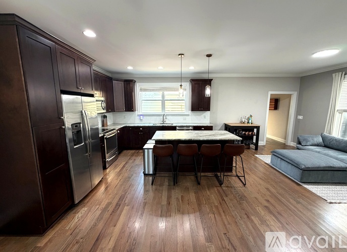 A kitchen with dark wood cabinets and a center island with four chairs.
