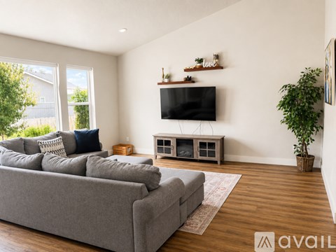 A living room with a grey sofa and a television on a cabinet.