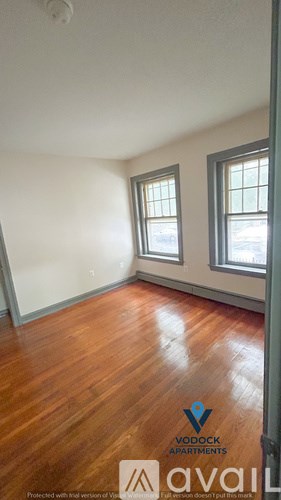 A room with wooden floors and two windows.