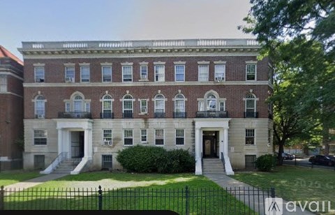 A large red brick building with a black fence in front.