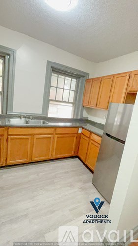 A kitchen with wooden cabinets and a stainless steel refrigerator.