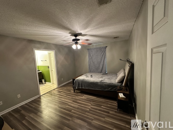 A bedroom with a bed, a ceiling fan, and a doorway leading to another room.