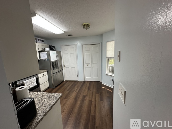 A kitchen with white cabinets and a wooden floor.