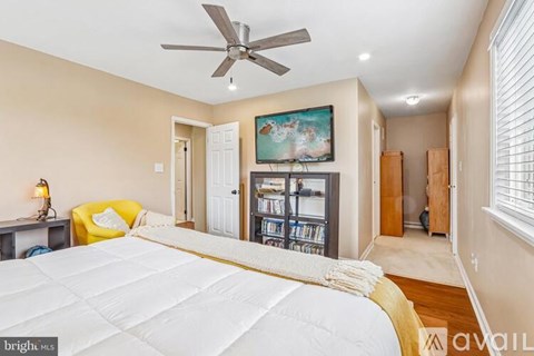A bedroom with a large bed and a ceiling fan.