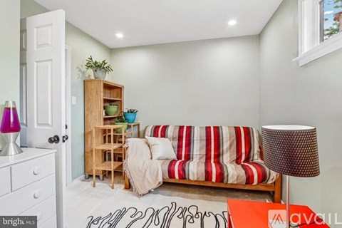 A living room with a striped couch and a wooden bookshelf.