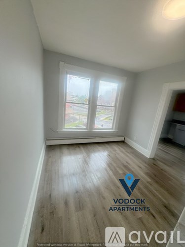 A room with wooden flooring and a window overlooking a street.