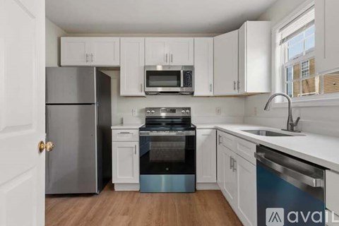 A kitchen with white cabinets and a wooden floor.