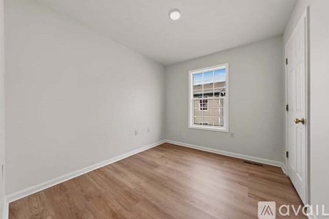 A room with wooden flooring and a window with blinds.
