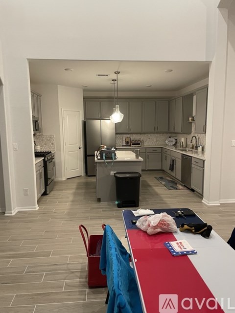 A kitchen with a red table and a blue chair.