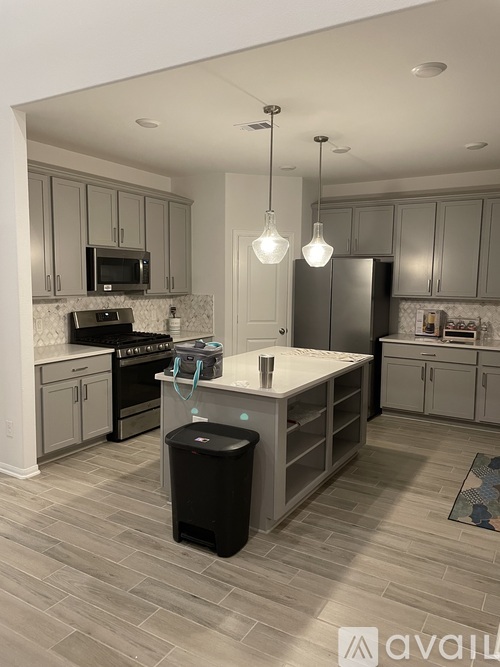 A kitchen with a black trash bin in the middle of the island.