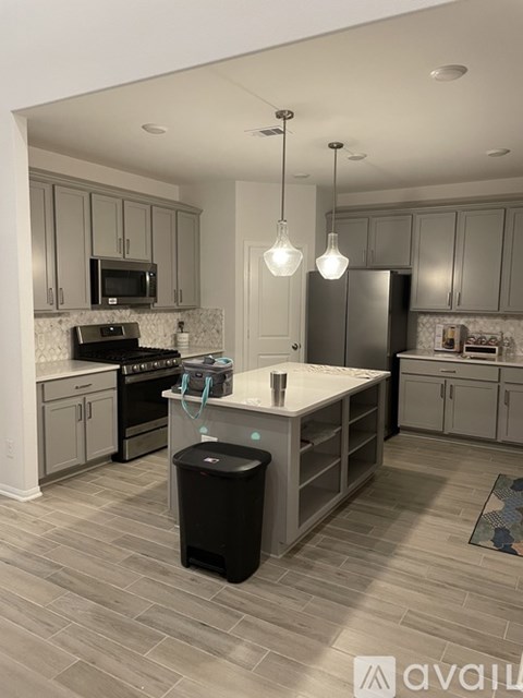 A kitchen with a black trash bin in the middle of the island.