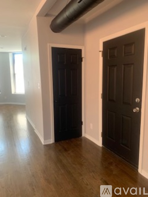 A room with a black door and a wooden floor.