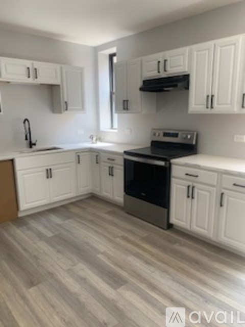 A kitchen with white cabinets and a black stove top oven.