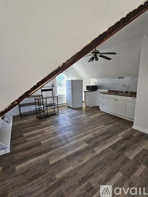 A kitchen with a wooden floor and a staircase leading to the upper floor.