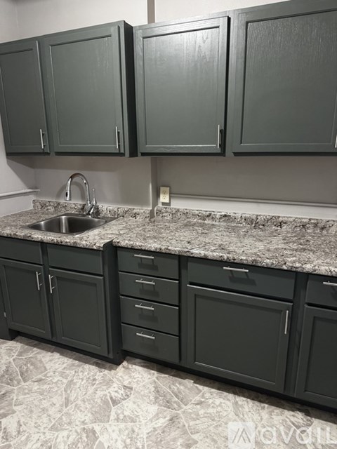A kitchen with dark green cabinets and a marble countertop.