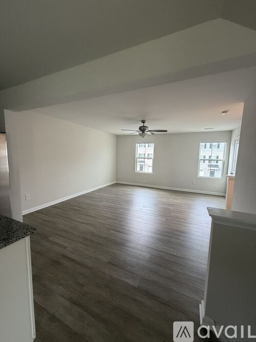 A spacious room with a ceiling fan and hardwood flooring.