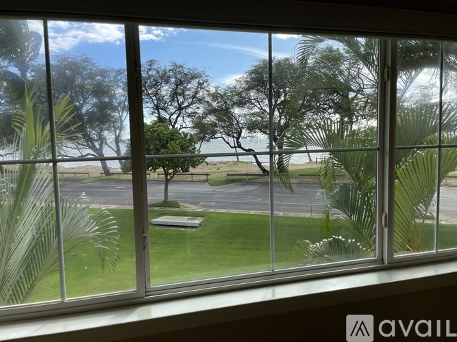 A view from a window looking out to a parking lot and trees.