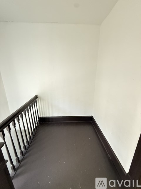 A staircase with a black railing and white walls.