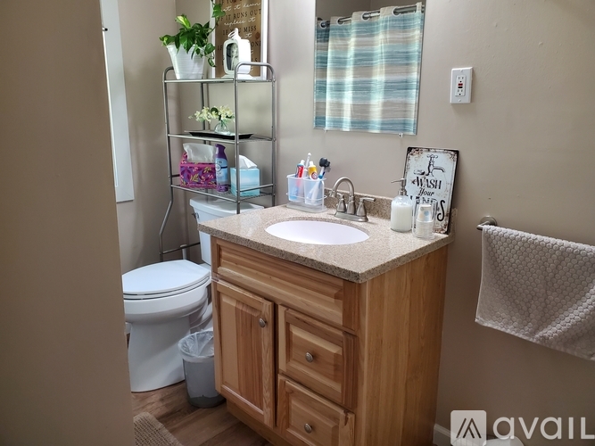 A bathroom with a white toilet, a sink with a wooden cabinet, and a towel hanging on the wall.