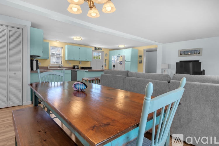 A kitchen with a table and chairs in the foreground and a living room in the background.