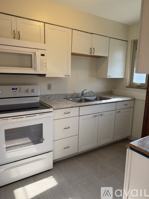 A kitchen with white appliances and cabinets.