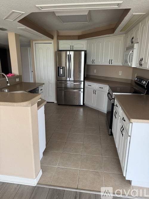 A kitchen with white cabinets and a stainless steel refrigerator.