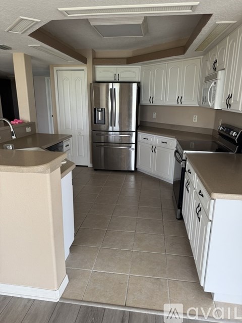 A kitchen with white cabinets and a stainless steel refrigerator.