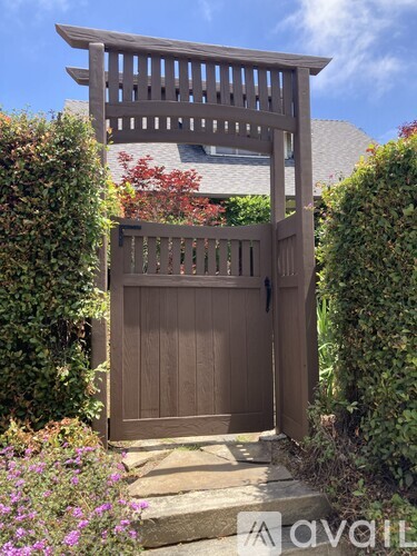 A wooden gate is closed with a wooden arch above it.