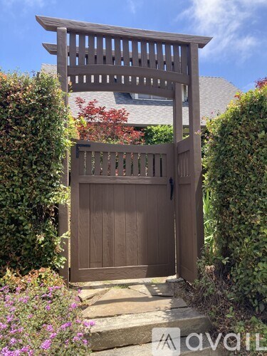 A wooden gate is closed with a wooden arch above it.