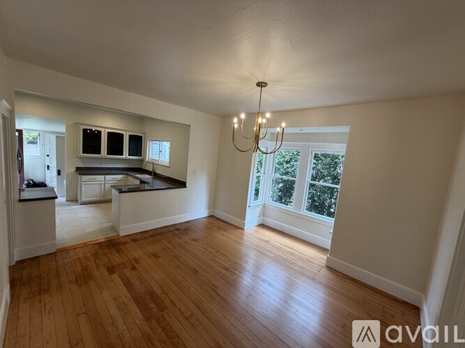 A spacious room with wooden floors and a chandelier.