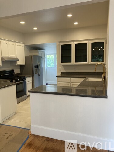 A kitchen with white cabinets and a black countertop.