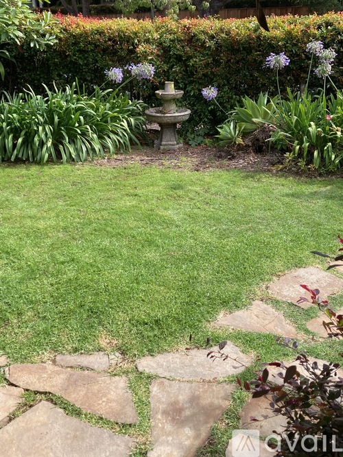 A garden with a fountain in the middle of a grassy area.