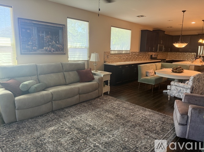 A living room with a grey couch and a painting on the wall.