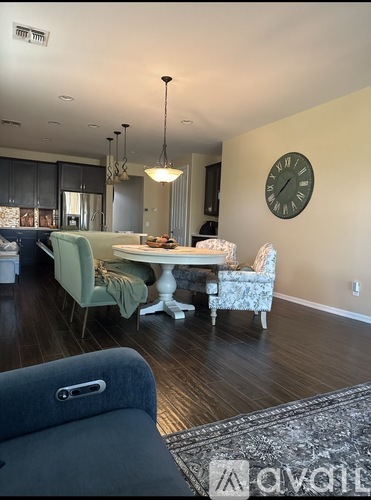 A dining room with a table set for two and a clock on the wall.
