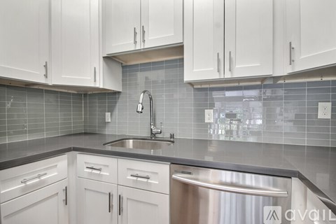 A kitchen with white cabinets and a stainless steel dishwasher.