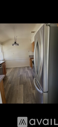 A kitchen with a refrigerator and wooden floors.